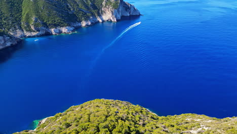 Toma-Aérea-De-Un-Dron-Volando-Sobre-Un-Increíble-Mar-Azul-Profundo-Junto-A-La-Playa-De-Navagio-En-Zakynthos,-Grecia-En-Un-Día-Soleado