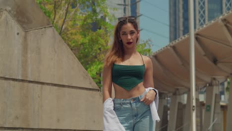 En-El-Corazón-De-Un-Paisaje-Urbano-Caribeño,-Una-Chica-Con-Jeans-Y-Botas-Explora,-Con-Edificios-Altos-Que-Ofrecen-Un-Sorprendente-Contraste.