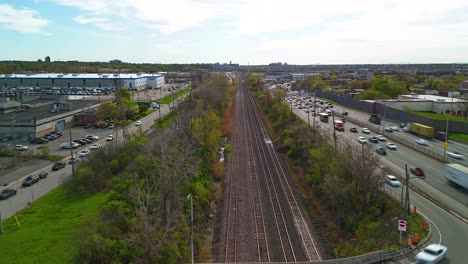 Aerial-hyper-lapse-drone-fly-above-with-railway-and-car-traffic-driving-in-rush-hours-in-metropolitan-suburban-area-of-big-modern-city,-air-pollution-concetp