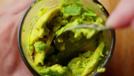 Avocado-pulp-in-a-glass-being-mixed-with-a-spoon