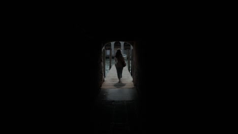 Mujer-Caminando-Por-Un-Camino-Oscuro-Hacia-El-Muelle-Del-Gran-Canal-En-Venecia,-Italia