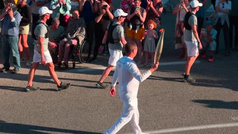 Olympic-torch-relay-event-in-Toulon-with-crowd-cheering-along-the-road,-sunny-day