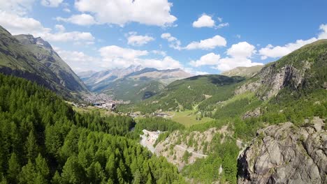 Vuelo-Sobre-Un-Bosque-En-Las-Hermosas-Montañas-De-Los-Alpes-Suizos-Con-La-Ciudad-De-Zermatt-Al-Fondo