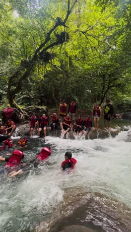 People-with-life-jackets-try-to-swimming-against-the-current-in-the-mountain-river