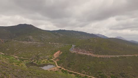 Drone-shot-of-the-mountains-in-Cederberg,-Cape-Town-with-a-glimpse-of-the-dam-in-the-middle-of-the-mountains-that-surround-it