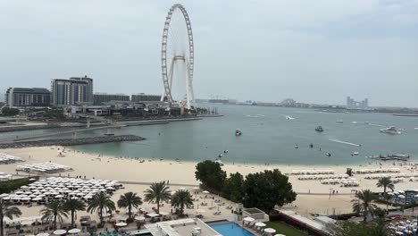 Stabiles-Stativvideo-Von-Einem-Luxuriösen-Strand-An-Der-Küste-Dubais-Mit-Luxusbooten-Und-Jetskis,-Die-An-Einem-Sehr-Heißen-Und-Bewölkten-Tag-Am-Meer-Auf-Dem-Wasser-Herumfahren