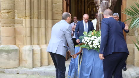 Men-and-women-at-a-church-entrance-during-a-Spanish-Communion-ceremony,-daylight-setting