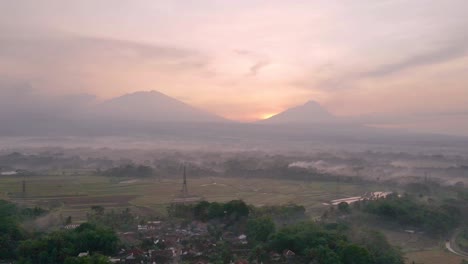 Indonesia-countryside-and-silhouette-of-mountains-in-early-misty-morning,-aerial-view