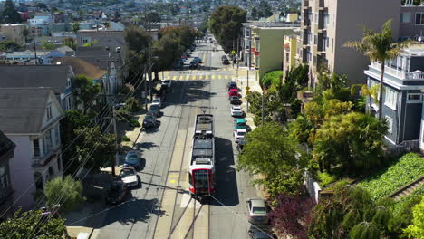 Drone-following-a-light-rail-on-the-streets-of-San-Francisco,-sunny-day-in-CA,-USA