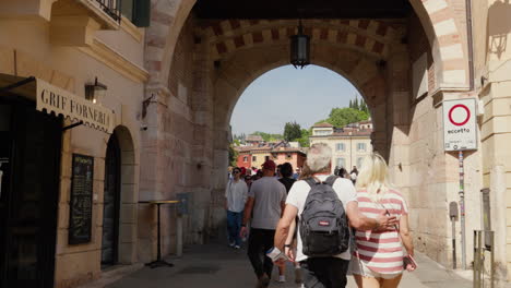 Tourists-strolling-under-ancient-archway-in-sunny-Verona