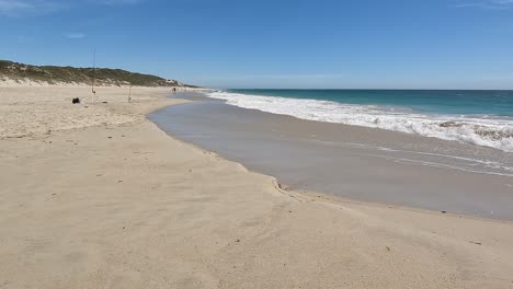 Handkamera-Clip,-Der-Die-Wellen-Zeigt,-Die-An-Einem-Strand-Mit-Dünen-Und-Angelruten-Brechen