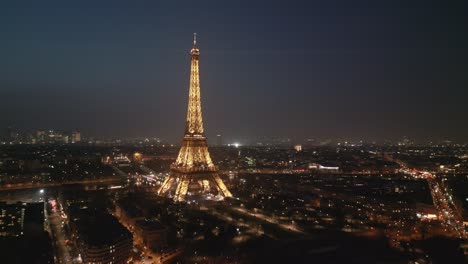 Recorra-La-Torre-Eiffel-Iluminada-Por-La-Noche-Mientras-Se-Ilumina-Con-Un-Espectáculo-De-Luces-Desde-Arriba,-El-Paisaje-Urbano-De-París,-Francia
