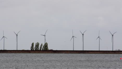 wide-shot-at-wind-turbines-moving-in-the-wind-at-Covenham-Reservoir-Covenham-at-St-Bartholomew,-Louth