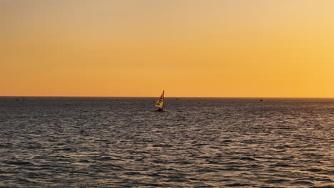 Pequeño-Bote-Velero-Atardecer-Navegando-Sobre-Mar-Abierto