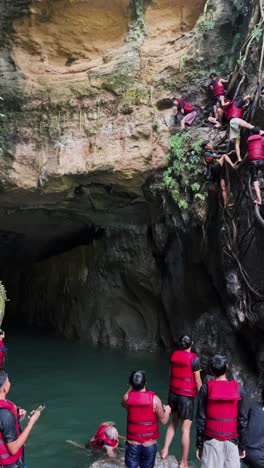 A-boy-afraid-to-jump-off-from-a-cliff-while-his-friends-climbing-the-root-of-tree-and-others-waiting-on-below