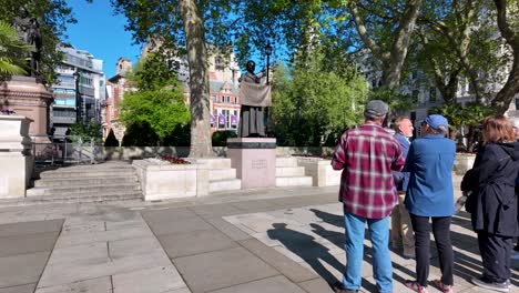 Grupo-De-Turistas-Frente-A-La-Estatua-De-Millicent-Garrett-Fawcett-En-El-Jardín-De-La-Plaza-Del-Parlamento-En-Londres,-Reino-Unido.