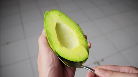 Closeup-of-fresh-green-avocado-flesh-being-scooped-out-using-spoon