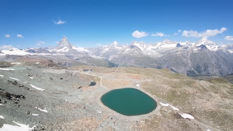 Panoramic-aerial-view-of-an-Alpine-lake-and-Swiss-Alps-in-the-background,-located-at-Gornergrat,-Zermatt,-Switzerland