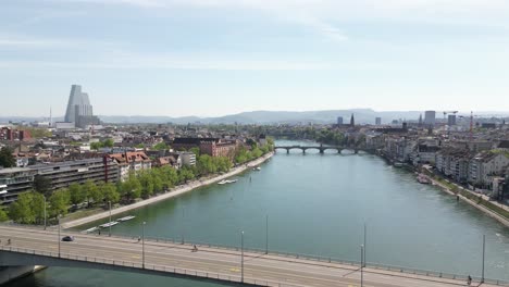 From-an-aerial-vantage-point,-Basel,-Switzerland's-residential-district-gracefully-aligns-with-the-flowing-Rhine-River,-embodying-the-seamless-coexistence-of-city-life-and-natural-watercourses