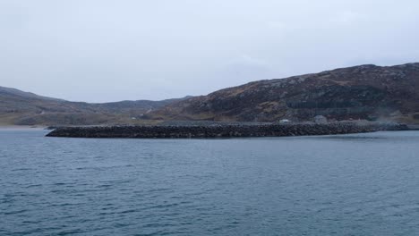 Approaching-Isle-of-South-Uist-in-the-Outer-Hebrides-of-Scotland-on-passenger-ferry-with-landscape-view-of-island-and-harbour