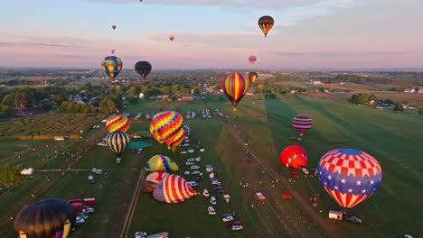 Una-Flota-De-Vibrantes-Globos-Aerostáticos-Se-Eleva-Suavemente-Hacia-Un-Cálido-Cielo-Al-Atardecer-Sobre-Un-Sereno-Paisaje-Rural