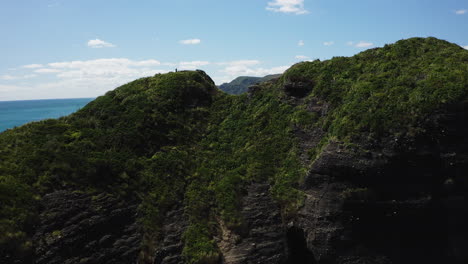 Drohnenaufnahme-über-Einer-Klippe-Mit-Blick-Auf-Das-Türkisfarbene-Meer-Und-Die-Küste-Am-Piha-Beach,-Neuseeland