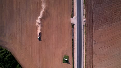 Aerial-top-down-tracking-follows-tractor-with-dust-cloud-rising-behind