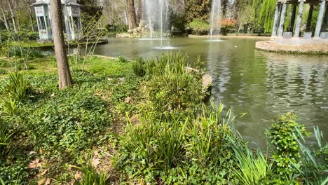 Mit-Einer-Kameraansicht-Sehen-Wir-Den-Chinesischen-Teich-In-Den-Jardines-De-El-Principe-Mit-Seiner-üppigen-Vegetation,-Seinem-Blauen-Marmortempel-Und-Seinem-Hölzernen-Vogelhaus,-Es-Gibt-Enten-Und-Wasserfontänen