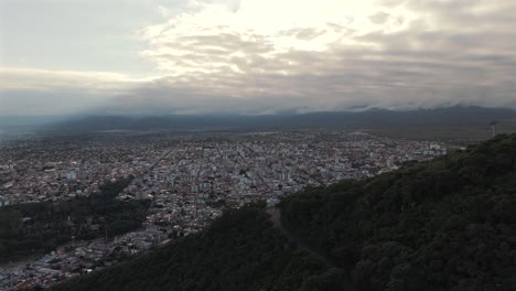 Aerial-Push-Along-Forested-Mountainside,-Overlooking-Salta,-Capital-City-Of-Argentina