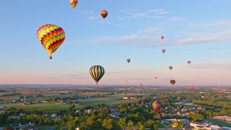 Globos-Aerostáticos-Vuelan-Sobre-Un-Entorno-Rural-Tranquilo,-Bañados-Por-El-Cálido-Resplandor-De-La-Luz-De-La-Mañana.