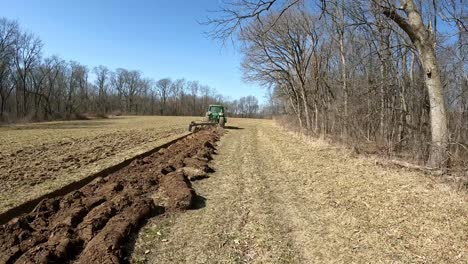 Nach-Einem-Landwirtschaftlichen-Traktor,-Der-Einen-Pflug-Durch-Ein-Leeres-Feld-Im-Frühen-Frühling-Im-Mittleren-Westen-Zieht