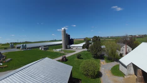 Establishing-drone-shot-over-farm-house-with-barn,-silo-storage-for-grain-and-stables