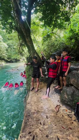 Junge-In-Schwimmweste-Schwingt-Mit-Einem-Seil-Und-Springt-In-Den-Fluss