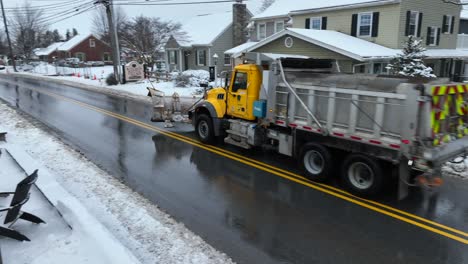 Snow-plow-driving-through-town-street-after-snow-storm