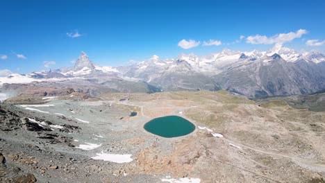 Panoramic-aerial-view-of-an-Alpine-lake-and-Swiss-Alps-in-the-background,-located-at-Gornergrat,-Zermatt,-Switzerland