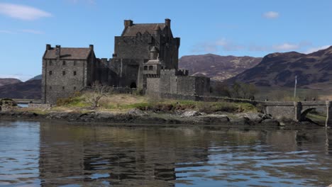 Slow-panning-shot-of-tourists-posing-with-Eilean-Donan-Castle-behind