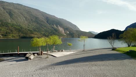 Ruhiger-Blick-Auf-Den-Molvenosee,-Umgeben-Von-üppigen-Bergen,-Mit-Einer-Ruhigen-Uferpromenade-Und-Leuchtend-Grünen-Bäumen