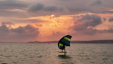 Sunset-Wing-Foiling:-Windsurfer-Riding-Upwind-On-A-Hydrofoil-Surfboard