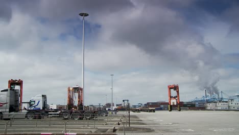 Wide-shot-of-a-busy-industrial-port-with-trucks-and-cranes-under-a-cloudy-sky