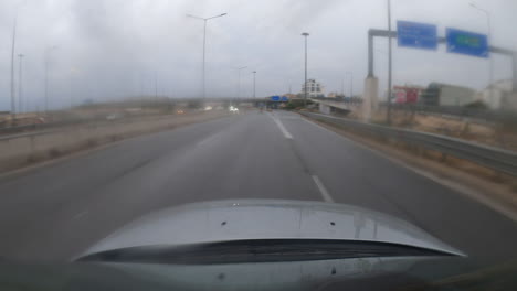 A-dynamic-hyperlapse-from-a-sports-camera-mounted-on-a-car-roof,-driving-through-Greece-towards-Athens-on-an-expressway,-capturing-a-journey-through-a-lit-tunnel-in-the-rain