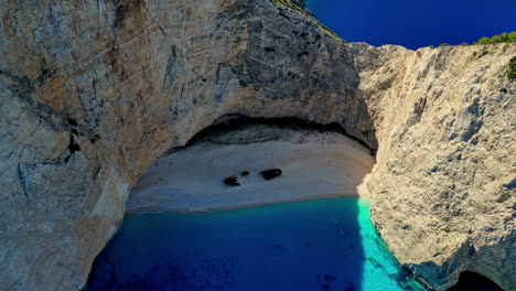 Playa-Navagio,-Isla-Zakynthos,-Grecia,-Vista-Aérea-Del-Naufragio-Cubierto-De-Arena-Blanca-Bajo-Acantilados-Escarpados,-Disparo-De-Drone