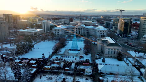 Denver-Christkindlmarket-in-snowy-Civic-Center-Park,-winter-sunset-aerial