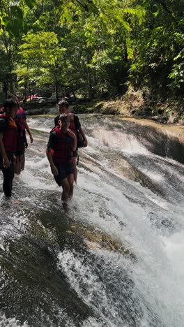 Teenage-boy-wearing-safety-jacket-and-raise-hands-before-jumping-into-the-waterfall