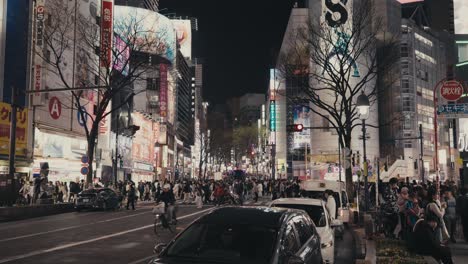 Multitud-De-Personas-Cruzando-Una-Calle-Muy-Transitada-Por-La-Noche-En-Tokio,-Japón