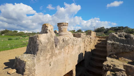 Estructura-De-Piedra-Parcialmente-En-Pie-En-Kato-Pafos-Con-Una-Base-De-Una-Sola-Columna-En-La-Parte-Superior,-Frente-A-Un-Cielo-Azul-Brillante-Y-Nubes-Esponjosas