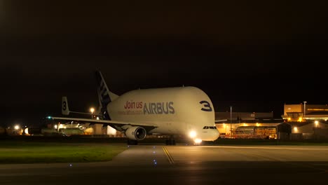 Nachtansicht-Eines-Airbus-Beluga-Flugzeugs-Auf-Einer-Landebahn-In-Saint-Nazaire,-Beleuchtet-Durch-Bodenlichter