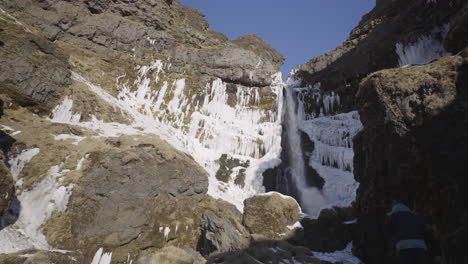 Caucasian-middle-age-walking-up-through-waterfall-canyon,-Iceland