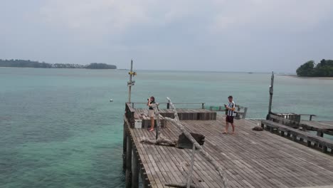 Vista-Aérea-De-Dos-Amigos-Al-Final-Del-Paseo-Marítimo-De-Canela-En-Koh-Mak,-Tailandia