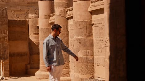 Hombre-Admirando-Los-Antiguos-Jeroglíficos-Egipcios-Sobre-Pilares-Dentro-Del-Complejo-Del-Templo-De-Philae.