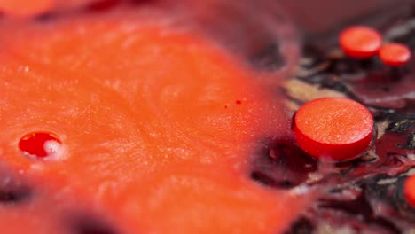 Close-up-of-vibrant-red-ink-drops-in-water-creating-abstract-patterns